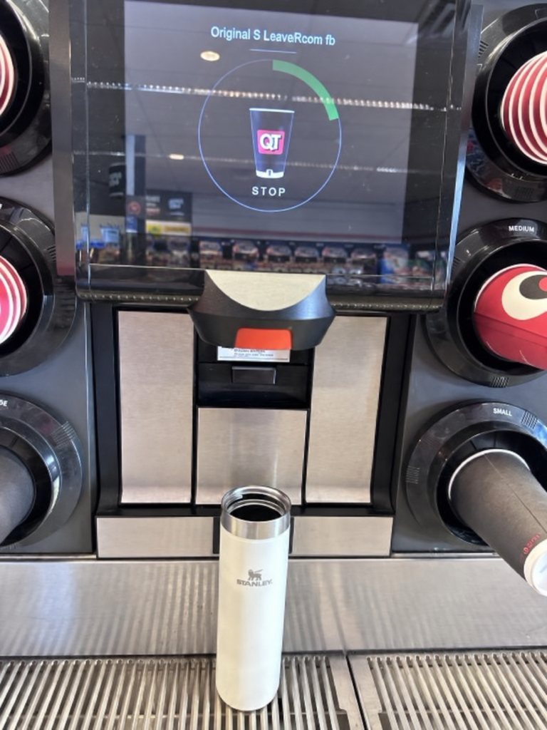 QTのコーヒーマシンから白いStanleyのボトルへコーヒーを注ぐ様子