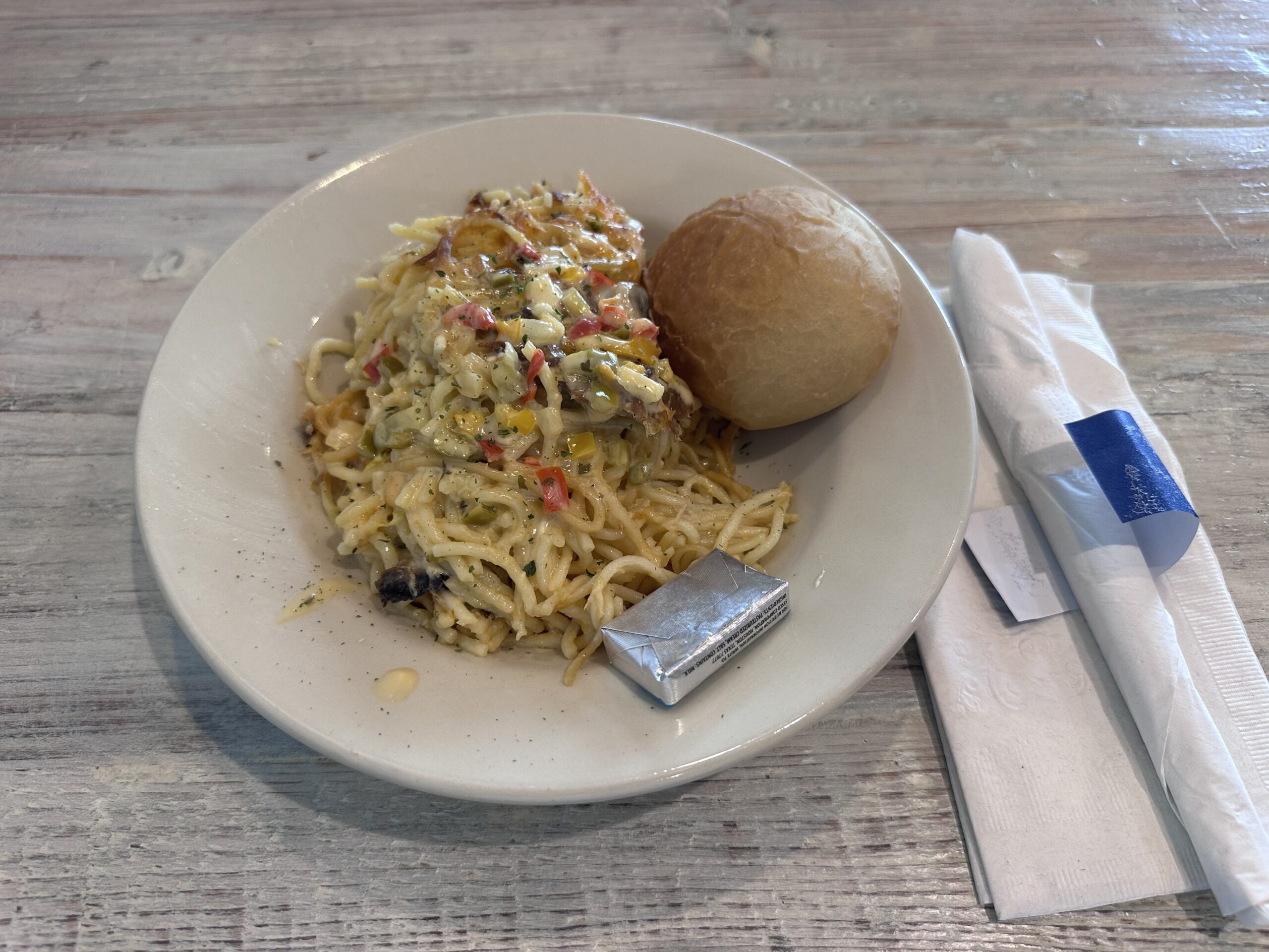 チキンスパゲティと丸いパン、個包装のバターを盛った皿