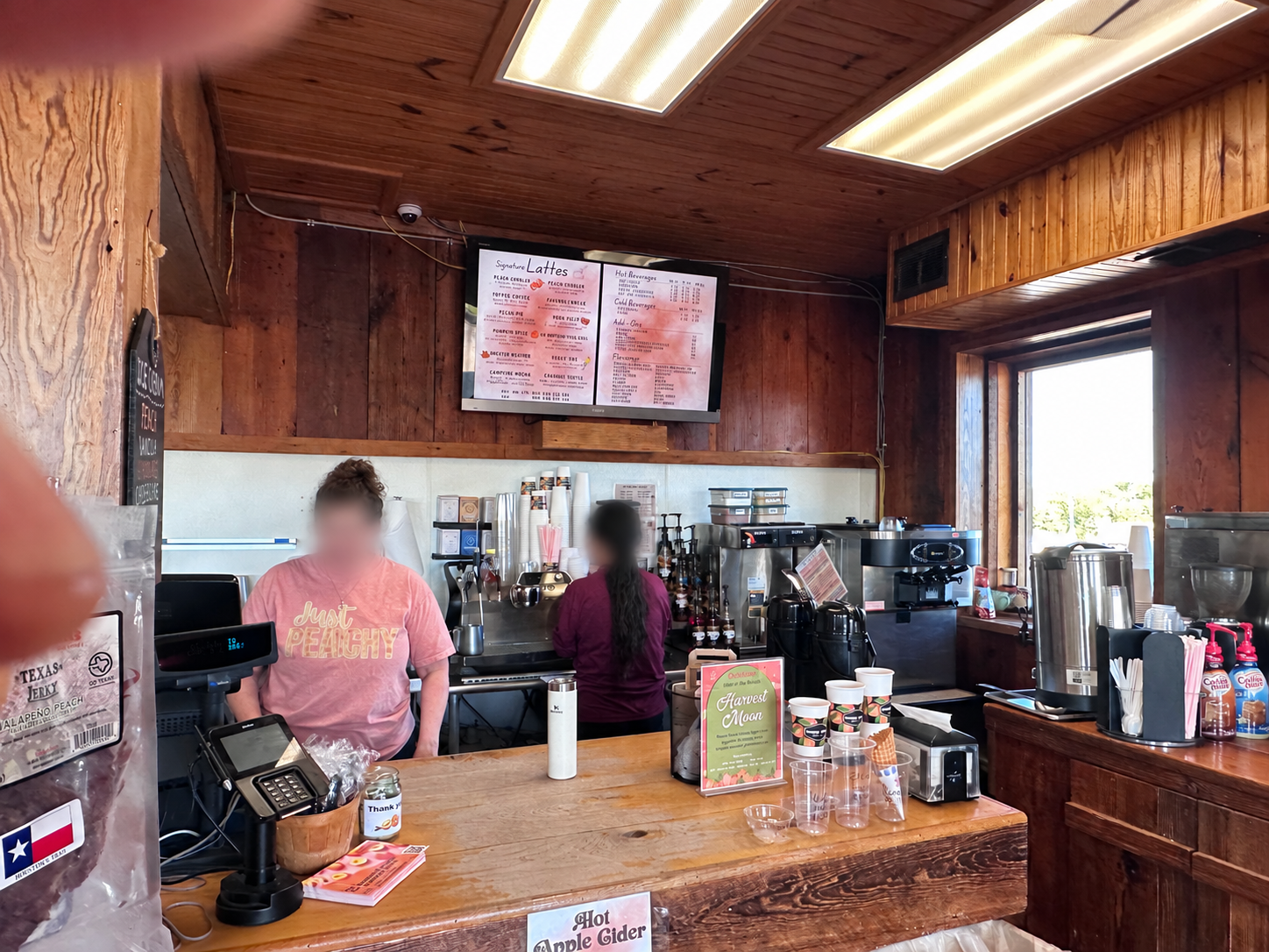木製のコーヒーカウンターに置いた白いStanleyのボトルと店員さん